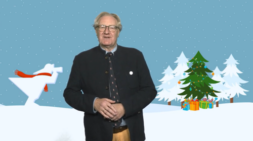 Der Rekto steht vor einem Hitnergrund, auf dem eine Grefik zu sehen ist, und hält seine Hände vor dem Bauch gefaltet. Die Grafik zeigt das Signet der Hochschule, den Fischer. Er schaut mit seinem FErnglas Richtung Winterwald.