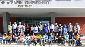 Gruppenfoto von Menschen vor einem Gebäude mit der Aufschrift 'Аграрен Университет Ректорат'