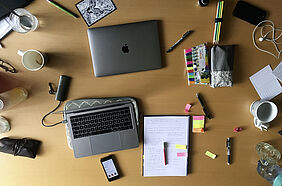 A table from above with laptops, note pads, highlighters and pens